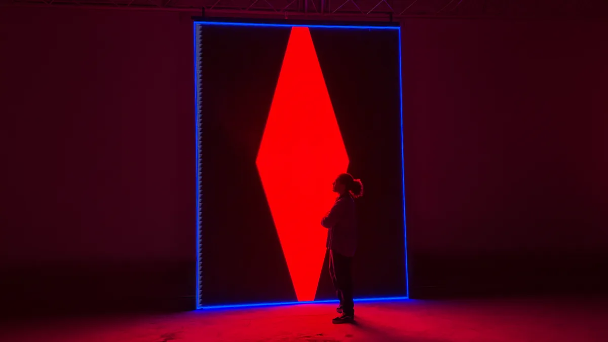 Visitor beside an LED-framed red diamond installation