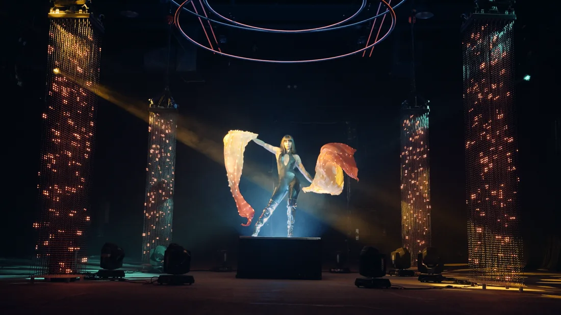 Aerialist in a cube suspended among blue volumetric beams