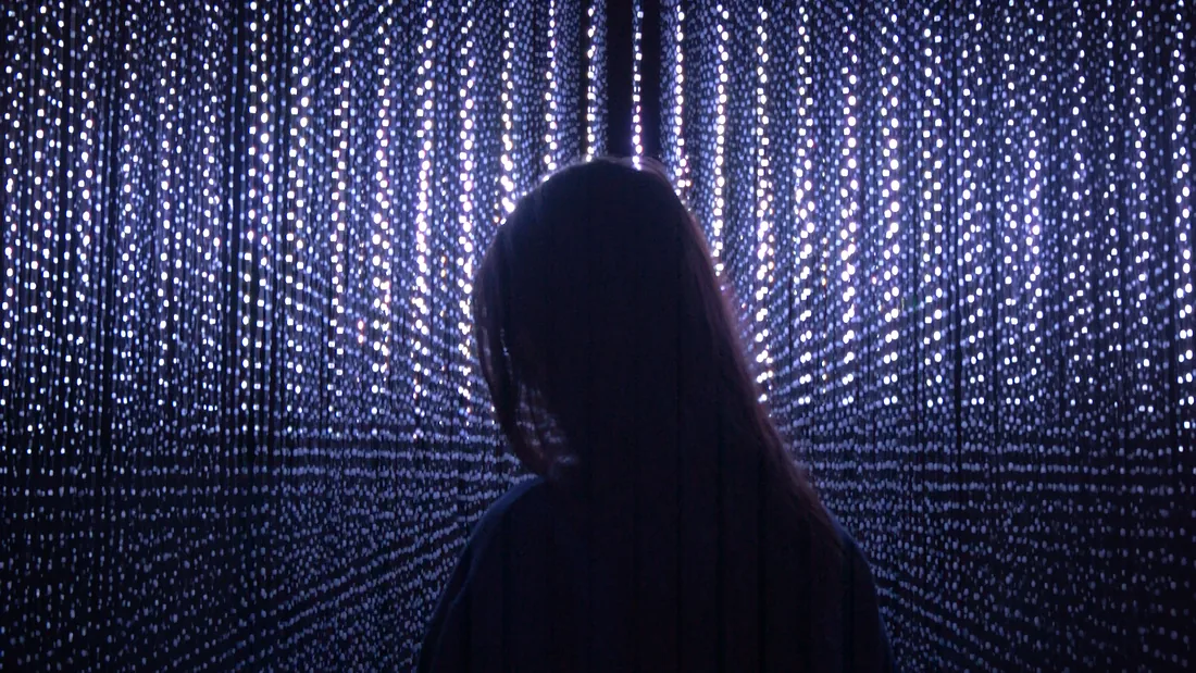 Single figure silhouetted against a dense curtain of light